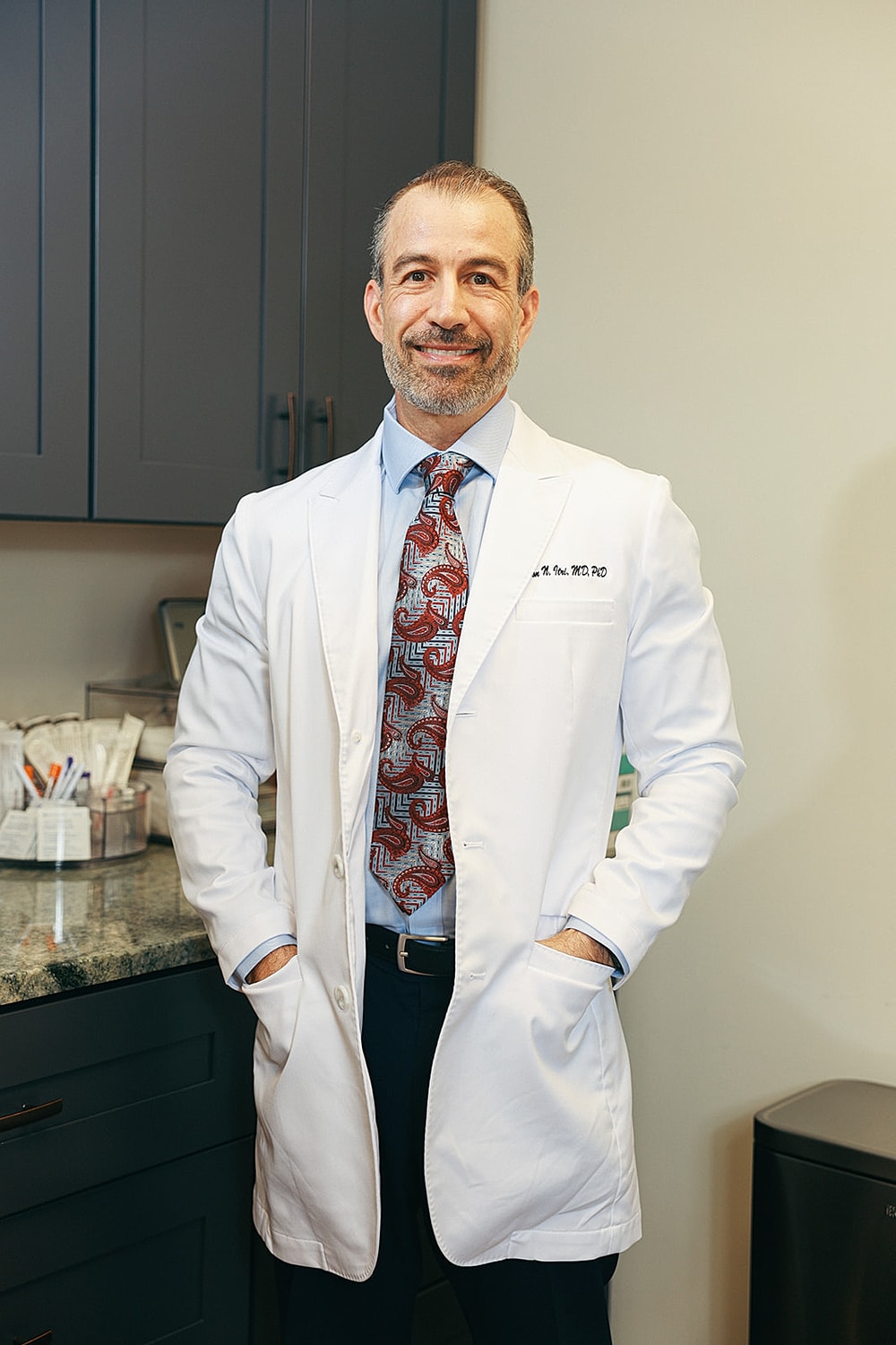 Doctor in white coat smiling in office setting.