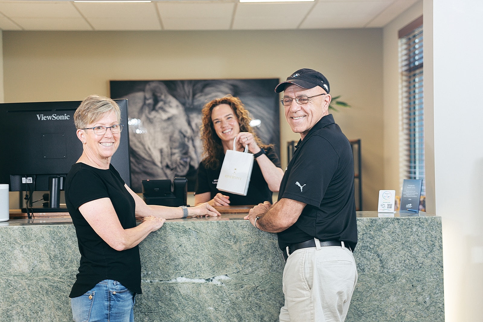 Smiling staff assisting customers at reception desk.